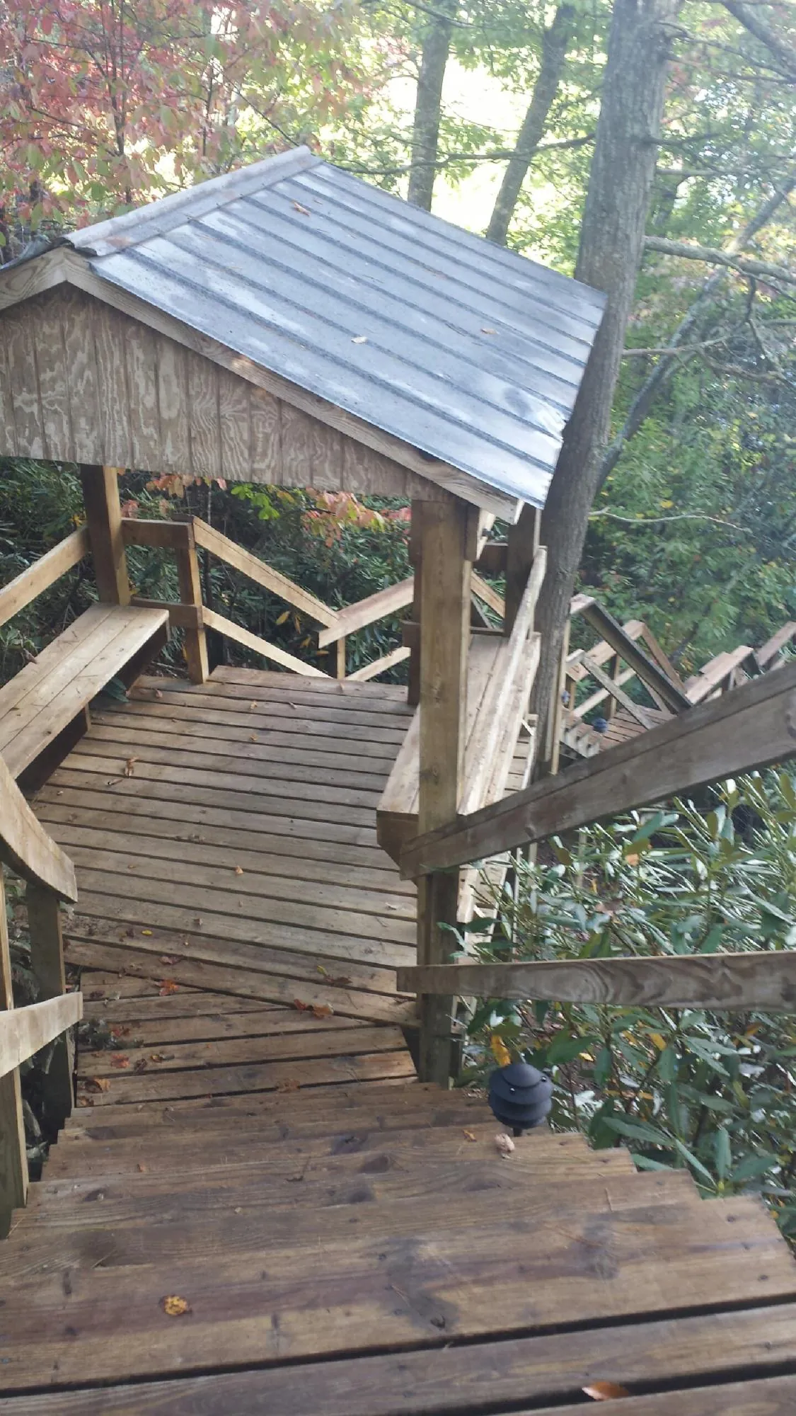 Metal roofed shelter over wooden steps on a wooded walkway — Skylight Repair & Installation work by our crew in Huntington